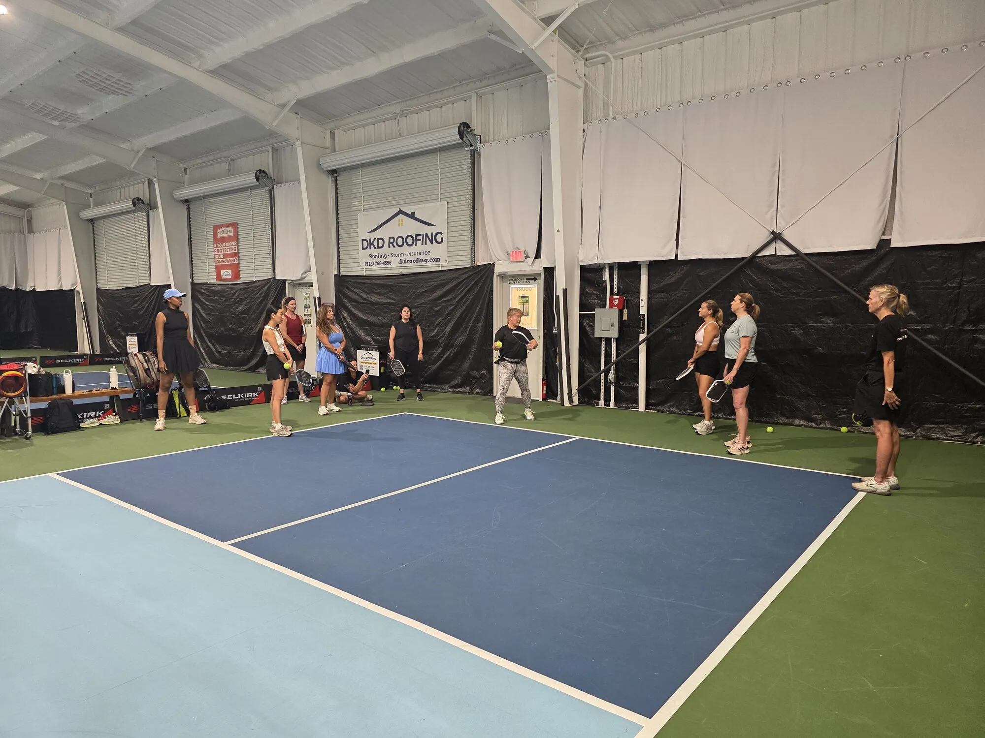 A group learning pickleball together on an indoor court at Pickle Pit Stop